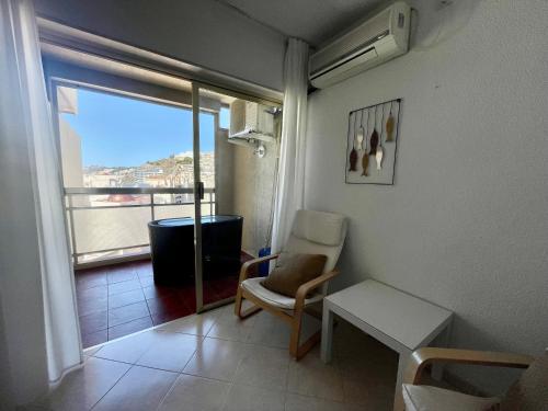 a room with a chair and a window with a view at Apartamentos Apal Chinasol in Almuñécar