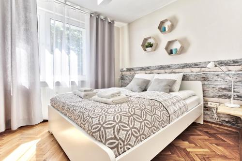 - une chambre blanche avec un grand lit et une fenêtre dans l'établissement Tyzenhauz Apartments Lobzowska Street, à Cracovie