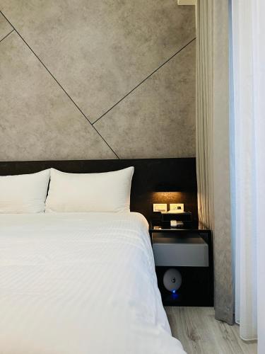 a bedroom with a large white bed and a side table at 北緯23點5度民宿-車位可預訂 in Hualien City