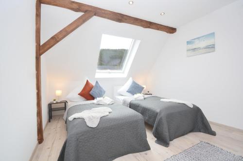 2 Betten in einem Zimmer mit weißen Wänden und Holzbalken in der Unterkunft GUN03-RI Apartment in Haundorf in Haundorf