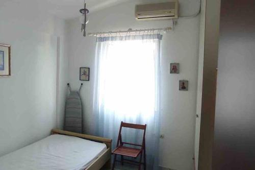 a bedroom with a bed and a chair and a window at Luxury Beach House 3 Br, AC in Selianitika