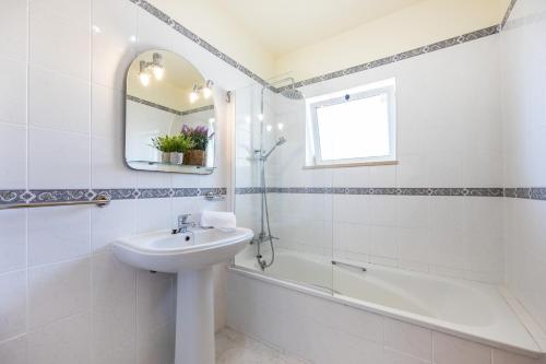 ein weißes Badezimmer mit einem Waschbecken, einer Badewanne und einem Spiegel in der Unterkunft Quinta do Paiva - Two Bedroom Apartment Olhos de Agua in Albufeira