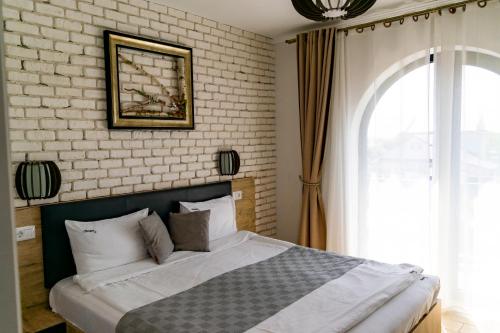 a bedroom with a bed and a brick wall at Boutique 23 in Douăzeci şi Trei August