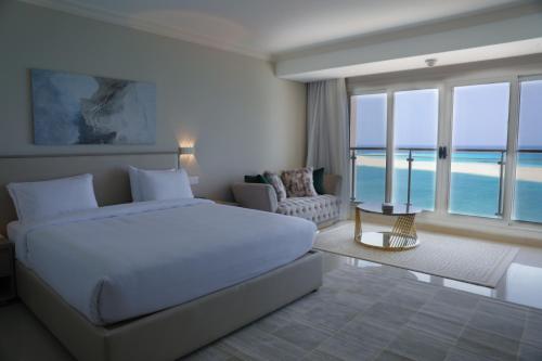 Triumph White Sands Hotel في مرسى مطروح: غرفة نوم بسرير ابيض ومطلة على المحيط