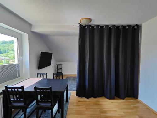 een zwart gordijn in een kamer met een tafel en stoelen bij SANO Apartments - DGL - Hagen Zentral - vollausgestattete Küche - Internet - Platz für bis zu 5 Personen in Hagen