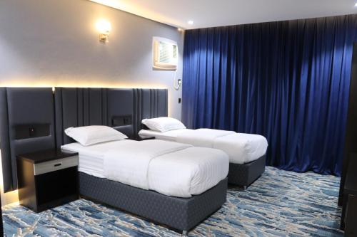 duas camas num quarto de hotel com cortinas azuis em قمم بارك Qimam Park Hotel 4 em Abha