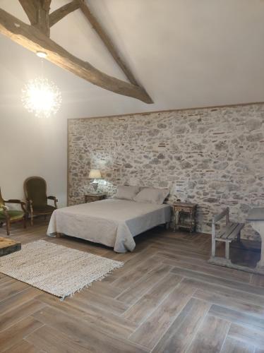 une chambre avec un lit et un mur en pierre dans l'établissement Le Domaine De Dolly, à Villeneuve-sur-Lot