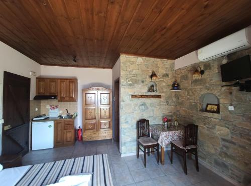 a kitchen with a stone wall and a table and chairs at Maistros Studios in Damouchari