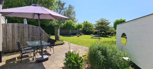 een patio met een parasol en een tafel en stoelen bij Roos Guesthouse Holiday Appartements in Schin op Geul