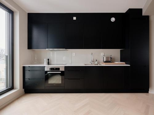 a kitchen with black cabinets and a sink at Fully serviced luxury apartment at Sommerro in Oslo
