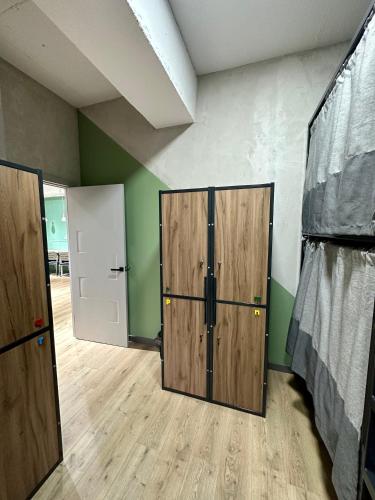 a room with two wooden doors and green walls at izzzi hostel in Bishkek