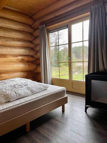a bedroom with a bed and a large window at Unieke houten villa met SAUNA in Twente - 6p in Den Ham