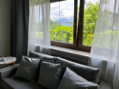 a couch with pillows sitting in front of a window at Aparthotel Hochfeld in Schönau am Königssee
