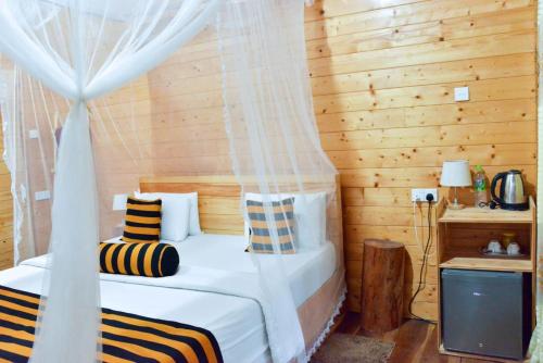 a bedroom with a bed with a canopy and a television at Eco Village in Ella