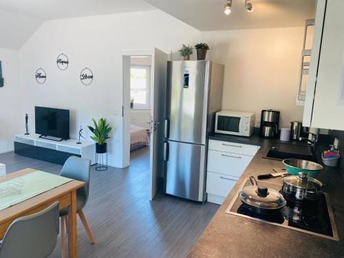 una cucina con frigorifero in acciaio inox e tavolo di Ferienwohnung Am Maarbach a Konz