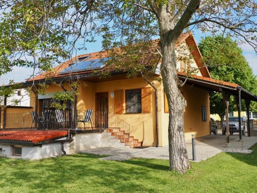 a yellow house with a porch and a tree at Ferienhaus Michi in St. Andrä am Zicksee