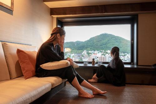 Dwie kobiety siedzące na kanapie patrzące przez okno w obiekcie La Vista Hakodate Bay w mieście Hakodate