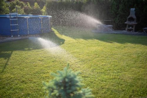a garden with a water sprinkler in the grass at MaMaison in Veresegyház