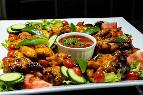 a plate of food with chicken and vegetables and sauce at African Sky Harrismith Inn in Harrismith