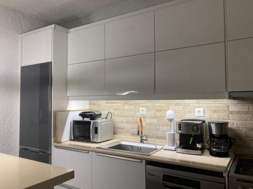 a kitchen with white cabinets and a sink and a microwave at Apartman Perea in Perea
