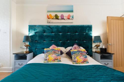 a bed with a blue headboard in a bedroom at Sea view Ar Lan y Mor LUXURY APARTMENT in Aberystwyth