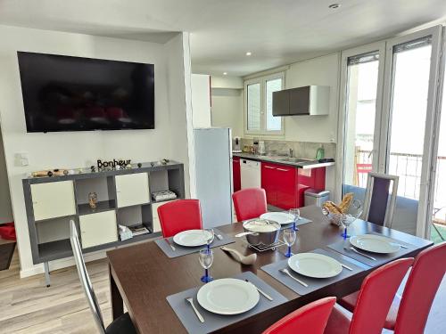 une cuisine et une salle à manger avec une table et des chaises rouges dans l'établissement Chez Louise, Appartement T3 à deux pas du centre, à Luchon