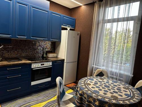 a kitchen with blue cabinets and a table and a refrigerator at VIP квартира подобово in Luts'k
