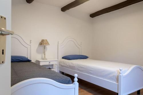 two beds in a bedroom with white walls at Rustico Porta in Brissago