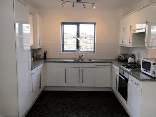 a kitchen with white cabinets and a sink and a window at The Waterwheel Apartment, Charlestown in Charlestown