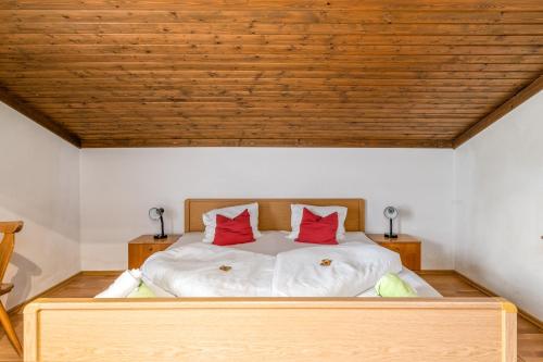 a bedroom with a bed with two red pillows on it at Panoramahotel Stocker in Pruggern