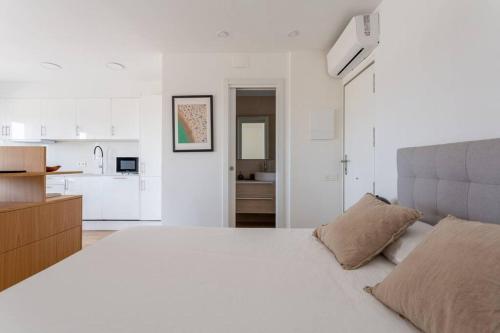 um quarto branco com uma cama grande e uma cozinha em A pie de playa en Gavá mar! em Gavà