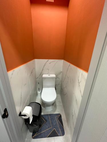 a small bathroom with a toilet and orange walls at izzzi hostel in Bishkek
