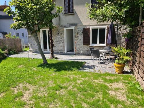 a house with a table and chairs in a yard at Gartenwohnung im Zentrum von Vira/Gamborogno in Vira