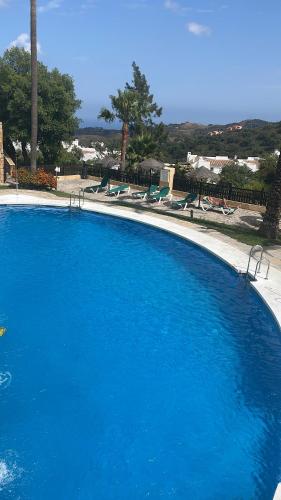 una grande piscina blu con sedie intorno di Mountain oasis with amazing ocean views a Ojén