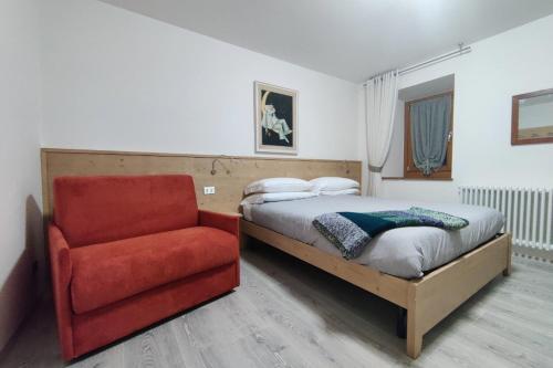 1 dormitorio con 1 cama y 1 silla roja en Tur Appartamenti, en Padola