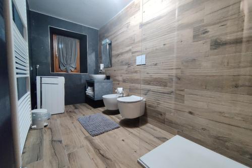 een badkamer met 2 toiletten en een houten muur bij Tur Appartamenti in Padola