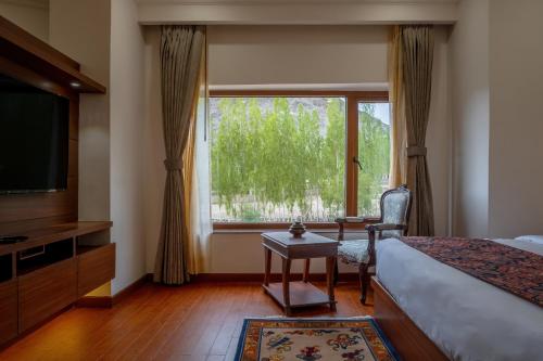 um quarto com uma cama, uma televisão e uma janela em Hotel Gyalpo Residency - A Mountain View Luxury Hotel in Leh em Leh