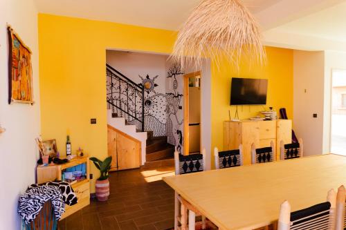 a dining room with yellow walls and a wooden table at Dar Mouja, eco-friendly home in Imsouane