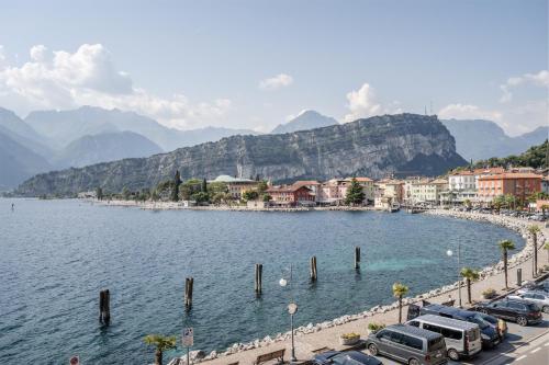 a city with cars parked next to a body of water at Windsurfer's Suite - Garda Lake View in Nago-Torbole