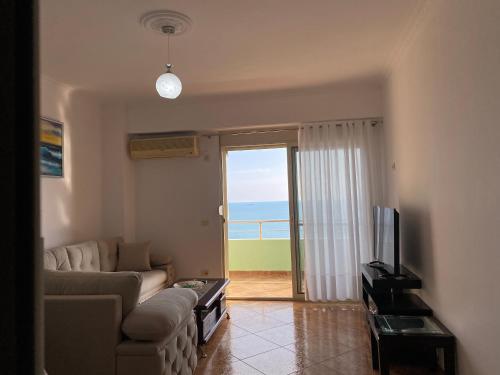 a living room with a couch and a television and a balcony at The Blue Pearl Apartment in Durrës