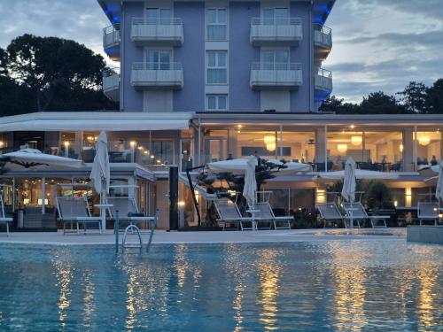 a hotel with chairs and umbrellas next to a pool at Fantinello Hotel in Caorle