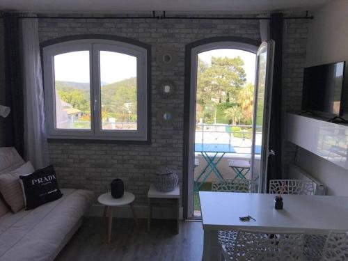 a living room with a couch and two windows at Les Issambres Superbe studio avec terrasse in Roquebrune-sur-Argens