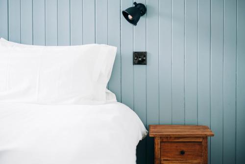 a bed with a white pillow and a wooden table at Bryn Berwyn Country House Tresaith in Penbryn
