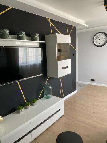 a living room with a white cabinet and a clock at Apartament Zeromskiego in Ostróda