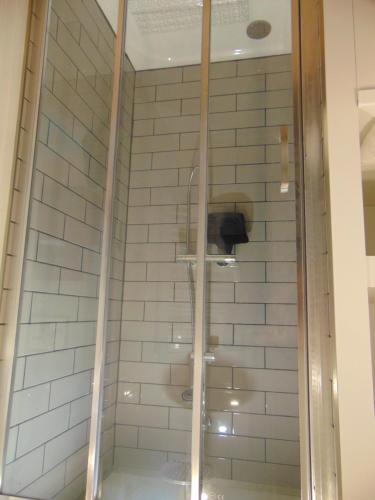 y baño con ducha y azulejos blancos. en La Vesiniere/BelleFleur gite, 