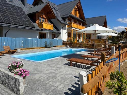 a swimming pool with benches and a house at W Dolinie Tylicza in Krynica Zdrój