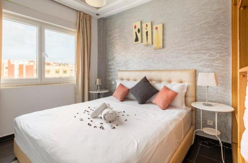een slaapkamer met een groot wit bed met bloemen erop bij Appartement 26 ensoleillé à 5 min de la plage El Jadida in El Jadida