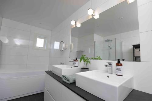 a white bathroom with a sink and a mirror at Sjønært hus på idylliske Husøy in Tønsberg