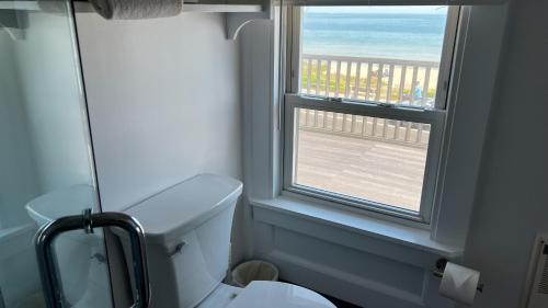 a bathroom with a toilet and a window with a view at Capricorn Beach House in Oak Bluffs