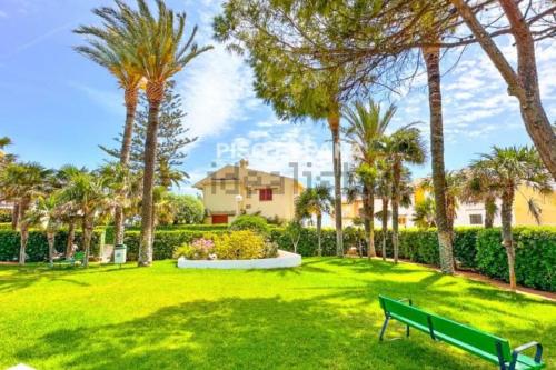 un parque con palmeras y un banco verde en Chalet PuigVal 50m de la playa en Valencia